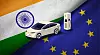 Electric car and charging station placed between India and EU flags.