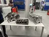 Engine housings and cylinder heads displayed on a white table in a factory hall.