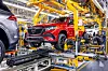 Red Mercedes-Benz SUV on an automated assembly line inside a car factory.