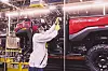 Worker assembling a red Honda Pioneer 1000 Deluxe on a factory production line.