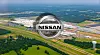 Aerial view of the Nissan vehicle plant complex beside a highway and green fields.