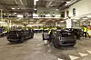 Volvo EX60 vehicles on a factory floor with workers in hi-vis vests watching.