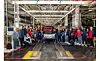 Group of factory workers standing around a Ram 1500 pickup on an assembly line.