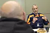 Factory manager in Volvo workwear speaks across a table during a meeting.