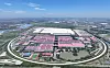 Aerial view of a large industrial complex with pink-roofed buildings, roads and greenery.