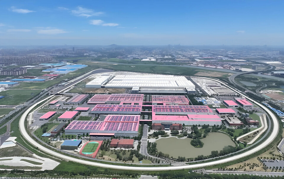 Aerial view of a large industrial complex with pink-roofed buildings, roads and greenery.