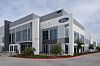 A modern Ford office and development building with large windows, the Ford logo and an EVDC sign outside.