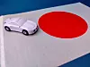 A white model car placed on a Japanese flag with a red circle.