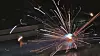 Bright welding sparks burst from a metal workpiece in a dim workshop.