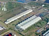 Aerial view of a large industrial plant with white-roofed factory buildings and nearby roads.