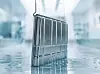 Chrome hard-shell luggage case standing on a reflective floor in a bright blurred interior.