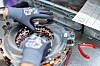 Gloved hands working on the copper coils of an electric motor assembly.