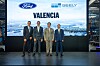 Four men stand on stage in suits in front of a large screen reading Valencia with Ford and Geely logos.