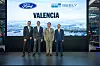 Four men stand on stage in suits in front of a large screen reading Valencia with Ford and Geely logos.