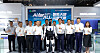 Group of people standing with two humanoid robots in front of a blue Shanghai Electric exhibition backdrop.