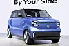 Blue Suzuki Vision e-Sky electric kei car concept shown in a studio with the words 'By Your Side' above it.