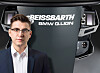 A man in a suit stands beside a Beissbarth BMW Q.Lign wheel alignment unit with a display and controls.