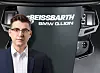A man in a suit stands beside a Beissbarth BMW Q.Lign wheel alignment unit with a display and controls.
