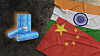 Blue battery cells lie next to overlapping India and China flags on a dark surface.