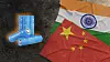 Blue battery cells lie next to overlapping India and China flags on a dark surface.