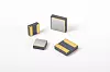 Four small rectangular battery cells with gold and grey casings arranged on a white background.