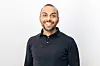 Smiling man wearing a dark polo shirt posed against a plain background.