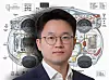 Portrait of a man in glasses in front of an electric vehicle wiring schematic.