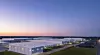 Aerial view of a battery storage site with white warehouse buildings and containers under a dusk sky.
