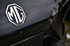 Close-up of an MG logo on the front of a black car.