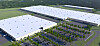 Aerial view of a large industrial complex with white-roofed buildings, parking lots and roads in a green landscape.