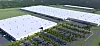 Aerial view of a large industrial complex with white-roofed buildings, parking lots and roads in a green landscape.