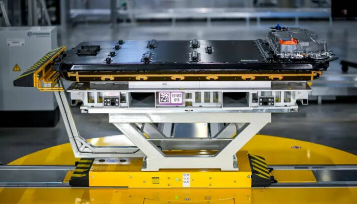 A servo-synchronous lifting table transports the high-voltage battery pack to the small assembly, where it is inserted under the body with millimetre precision, screwed in place, and connected.